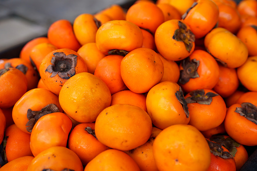 A stack of persimmons displayed for sale at a farmer's market.