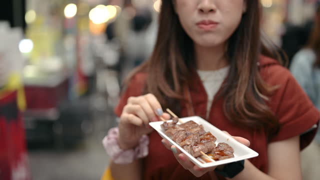 Close-up POV women pouring Steak sauce and pepper on grilled Wagyu stick japan streetfood