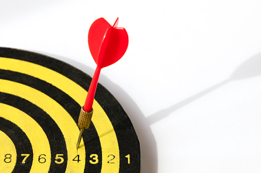 Closeup view of silhouette of three darts sticking in a professional sisal dartboard. All three darts hit the inner bull / bull's eye / mark.