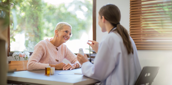 doctor discussion results or symptoms and gives Give advice about medicine to a senior women patient, giving consultation during medical examination in clinic.
