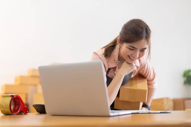 istock Asian woman entrepreneur prepare parcel box and check online order on laptop computer for commercial checking delivery. online marketing, packing box, SME seller. startup business concept 1798107357