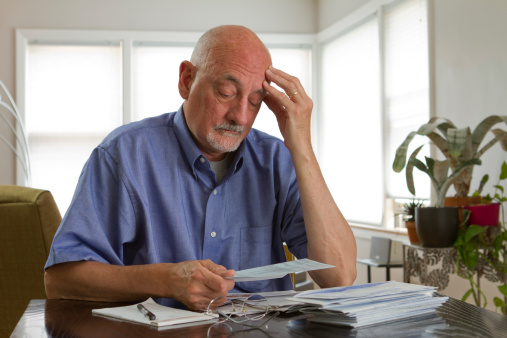 Older man frustrated while paying bills, horizontal