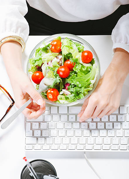istock Woman having a salad lunch whilst sat at her computer  179813854
