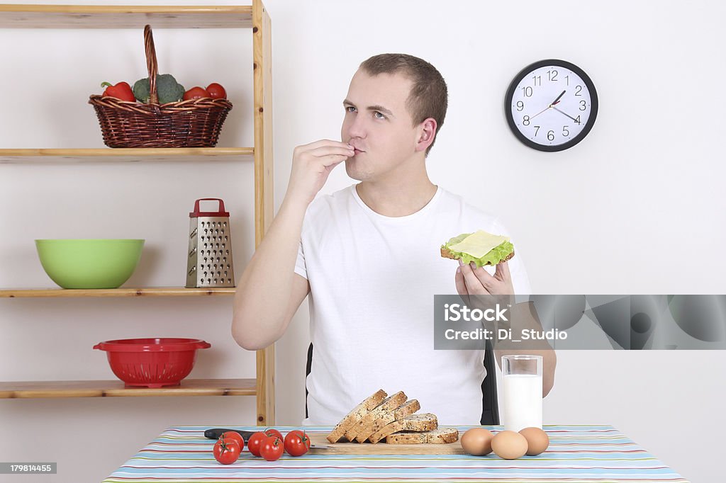 Hombre joven comiendo sabroso sándwich en la cocina - Foto de stock de Adulto libre de derechos
