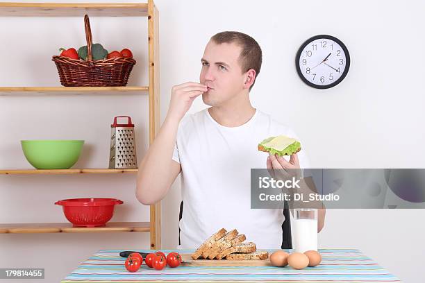 Hombre Joven Comiendo Sabroso Sándwich En La Cocina Foto de stock y más banco de imágenes de Adulto