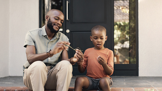 Smile, bonding and black man with child by the home playing together outdoor in backyard step. Happy, family and African father helping boy kid with building toys by modern house in South Africa.