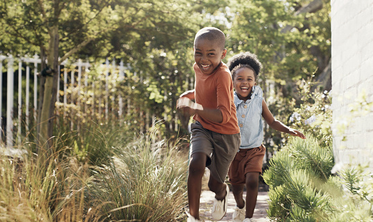 Happy, black kids running in garden and play game together outdoor at home. African children in backyard, excited and race or funny sister chase brother, bonding and laughing for freedom or energy