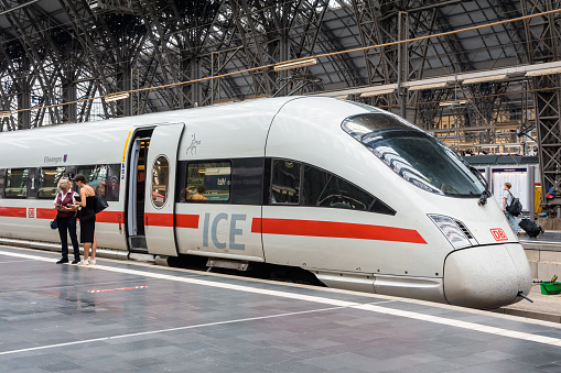 Frankfurt am Main, Germany - Aug. 19, 2023: An inspector checks the e-ticket of a young woman in front of an ICE high speed train from the Deutsche Bahn railway company in Frankfurt Central Station.