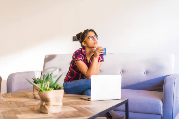 istock Pensive woman drinking coffee and using laptop at home 1798209290