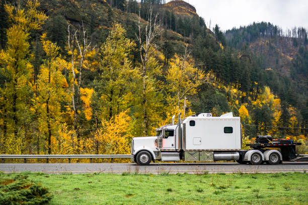 istock White big rig classic semi truck tractor with extended cab and step deck heavy duty semi trailer running on the autumn highway road 1798210616