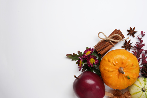 Autumn background with pumpkins, apples and dried leaves on white background. Top view, flat lay. Space for text.
