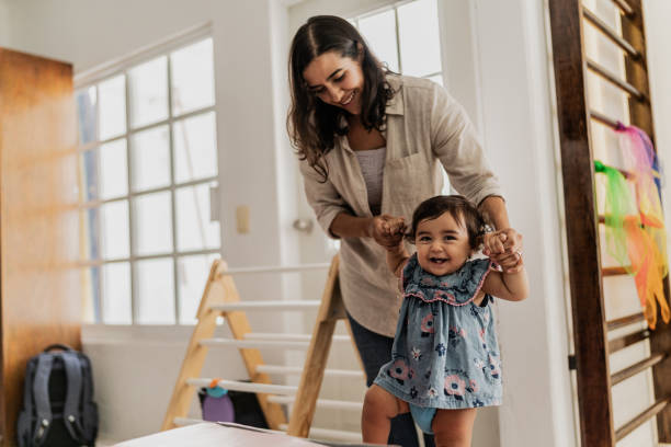 istock Mother supporting her daughter to take the first steps in the playroom 1798241232