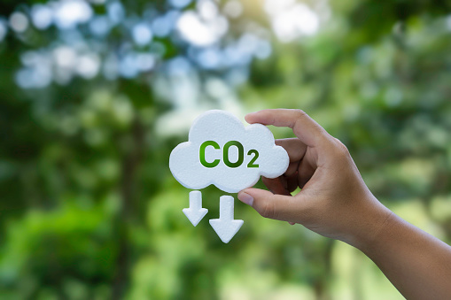 Hand holding a CO2 icon symbol. Net zero and carbon footprint for reduce emission, carbon neutral, limit climate change and global warming, and eco-friendly environment to green business