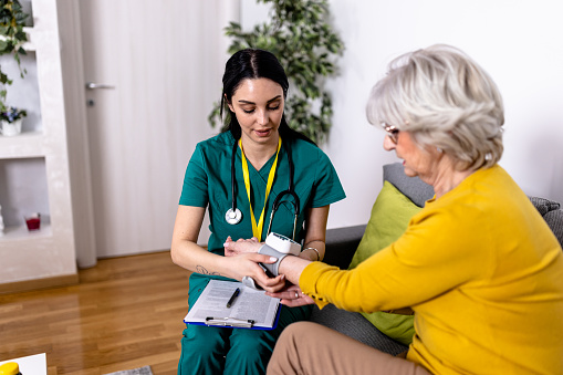Caregiver Monitors Senior Woman's Blood Pressure