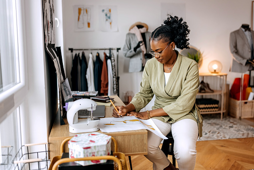 Young well dressed woman designing clothes at her small tailor workshop