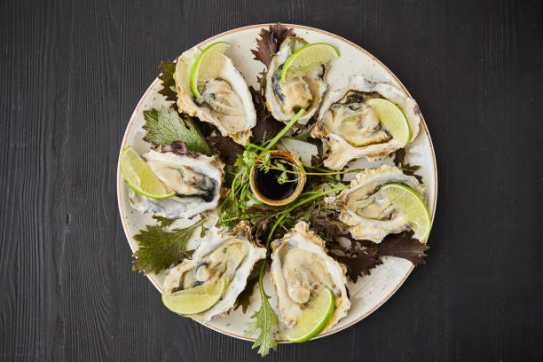 istock Cooked baked oysters in shells with lime slices, soy sauce and garnished with herbs. 1798297600