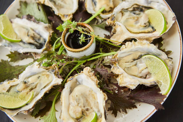 istock Cooked baked oysters in shells with lime slices, soy sauce and garnished with herbs. 1798298723