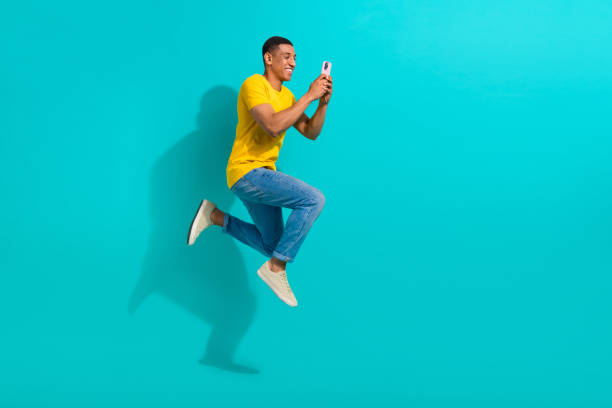 istock Full length profile portrait of excited handsome guy jump rush use smart phone empty space isolated on turquoise color background 1798300920