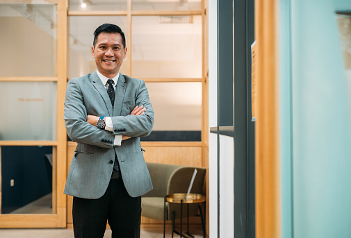 Portrait of a confident an Asian mutual businessman standing with his arms crossed in an office