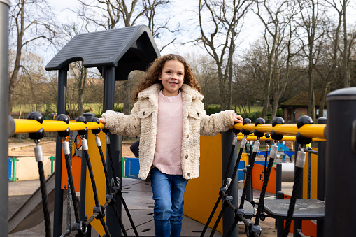 Three-quarter-length portrait of a young girl walking along a jungle gym in a public playpark. She is smiling, looking away from the camera. She is wearing warm clothing on a cold winter morning. The park is located in Gateshead.

Videos are also available for this scenario.
