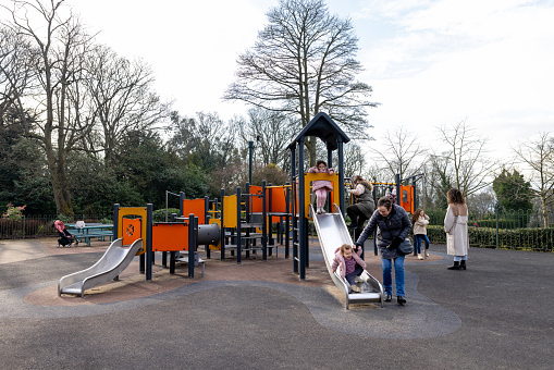 Full shot of a multi-generational family playing together at a jungle gym in a public park. A Grandmother with her two daughters, one who has Down syndrome and grandchildren all wearing warm clothing on a cold winter morning. The park is located in Gateshead.\n\nVideos are also available for this scenario.