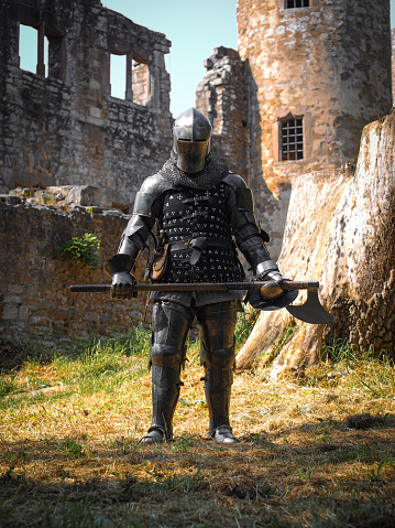 photography of a medieval knight in dark armor standing in front of a crumbling ruin, holding an axe