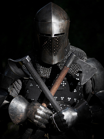 photography of a medieval knight in dark armor, holding an axe and a mace
