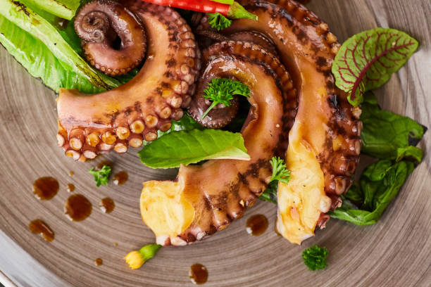 istock Seafood octopus or squid tentacles on a plate decorated with lime and lettuce. Decoration of flowers and herbs spices. A dish from the chef for serving 1798340669