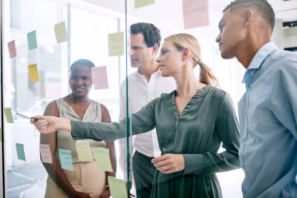 istock Vision, innovation and thinking with business people planning on sticky notes in an office. Creative teamwork collaboration on a goal and target while discussing a mission, design or target together 1798348367