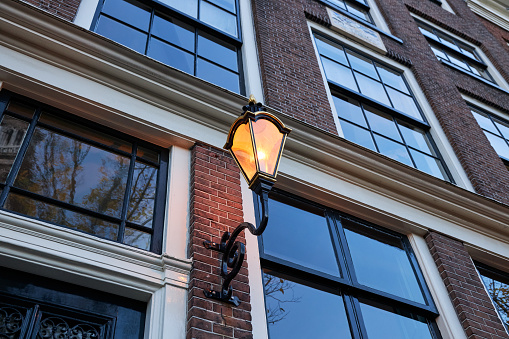 Historic canal house building facade with street lantern at dusk in Amsterdam, The Netherlands.