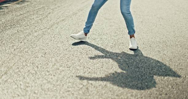 Feet, dancing and woman in city street for celebration, achievement or happy success with shadow or silhouette on asphalt road. Energy, freedom and urban hip hop dancer student girl legs and sneakers pies, baile y mujer en la calle de la ciudad para la celebración, el espacio de la maqueta o la energía con la sombra y la diversión. carretera asfaltada, libertad y pavimento urbano con piernas de persona y zapatillas deportivas con desplazamiento y pa