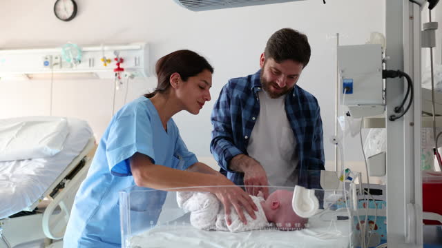 Midwife introducing a happy father to his newborn baby girl while she is in the incubator