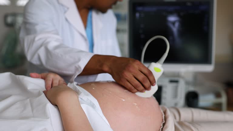 Unrecognizable doctor doing an ultrasound on pregnant woman at the hospital