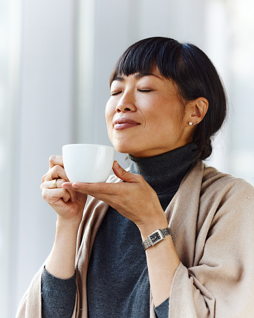 Young Japanese businesswoman enjoying in the smell of fresh coffee on a break. Copy space.