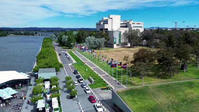 Drone aerial shot National art gallery The Jetty international flags boardwalk foreshore park Lake Burley Griffin Parliamentary zone Canberra travel tourism ACT Australia 4K