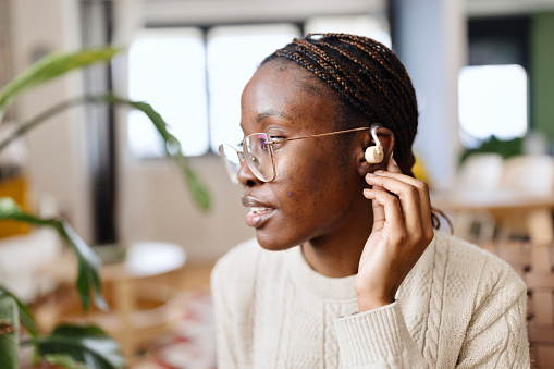 Close-up shot of a beautiful black woman wearing hearing device at home