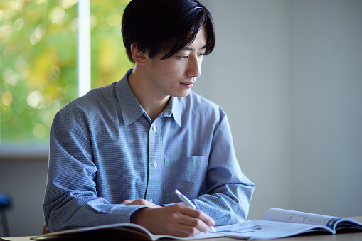 Japanese male university student studying in the living room