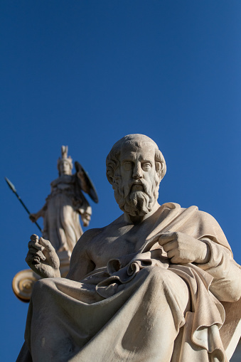 Marble statue of Greek philosopher Plato. Statue of goddess Athena on background.