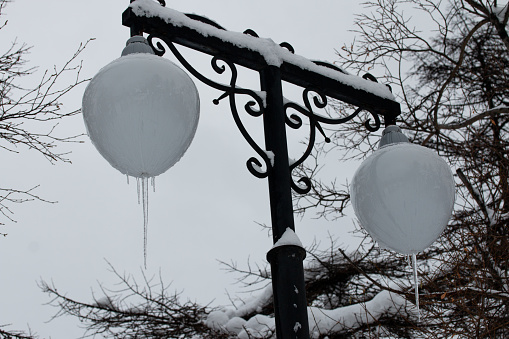 Street light in park covered with snow. Icicles hanging from the lamps. Picture of winter snowy Magadan city, Russia.