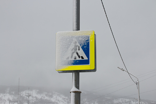 Picture of winter snowy Magadan city, Russia. Road sign covered with snow. Pedestrian walkway or crossing