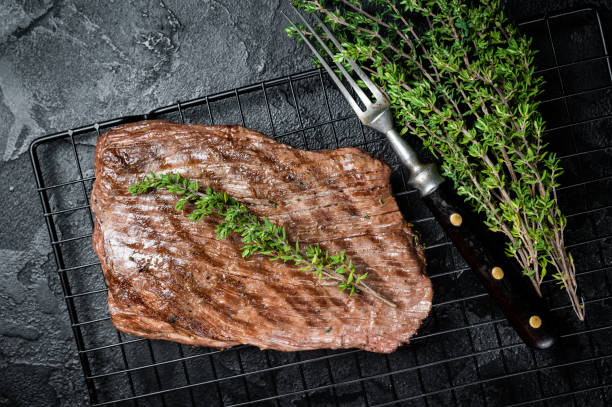 istock Roasted medium rare flank beef steak with thyme. Black background. Top view 1798442591