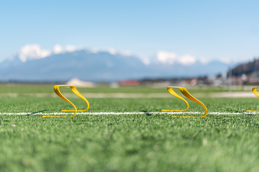 Close up image of two yellow hurdles outdoors on the green grass.