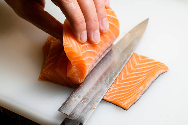 istock Professional chef cuts fresh salmon fillet with sharp knife on white cutting surface 1798466947