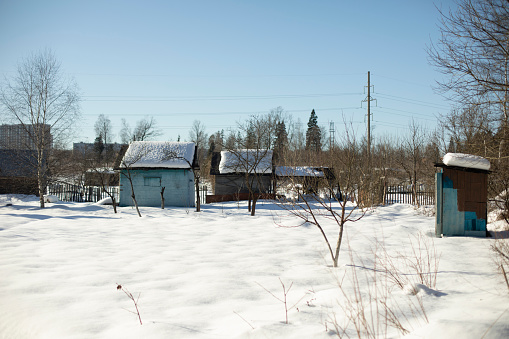 Winter in the village. Small house in a snowy field. Sheds in the snow. Old buildings.