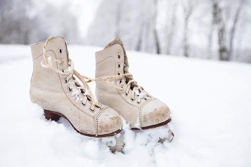 Old tattered skates against the backdrop of snowy nature. Winter background.