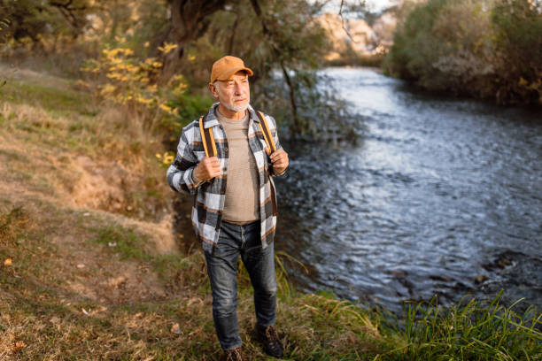 istock Senior man with backpack walking by the river on autumn day 1798496158