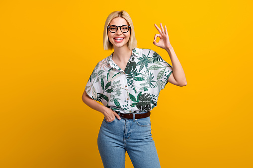 Photo portrait of lovely young lady showing okey symbol marketer hr wear trendy leaves print garment isolated on yellow color background.