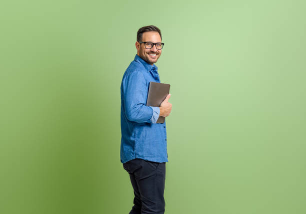 istock Side view of handsome smiling entrepreneur with digital tablet standing on isolated green background 1798502173