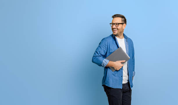 istock Smiling businessman holding digital tablet and looking over shoulder on blue background 1798502174