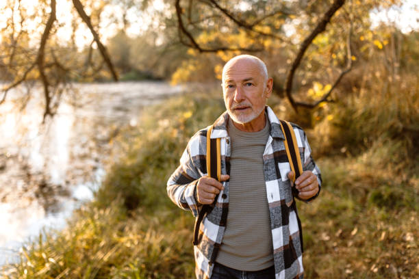 istock Senior man with backpack walking by the river on autumn day 1798506010